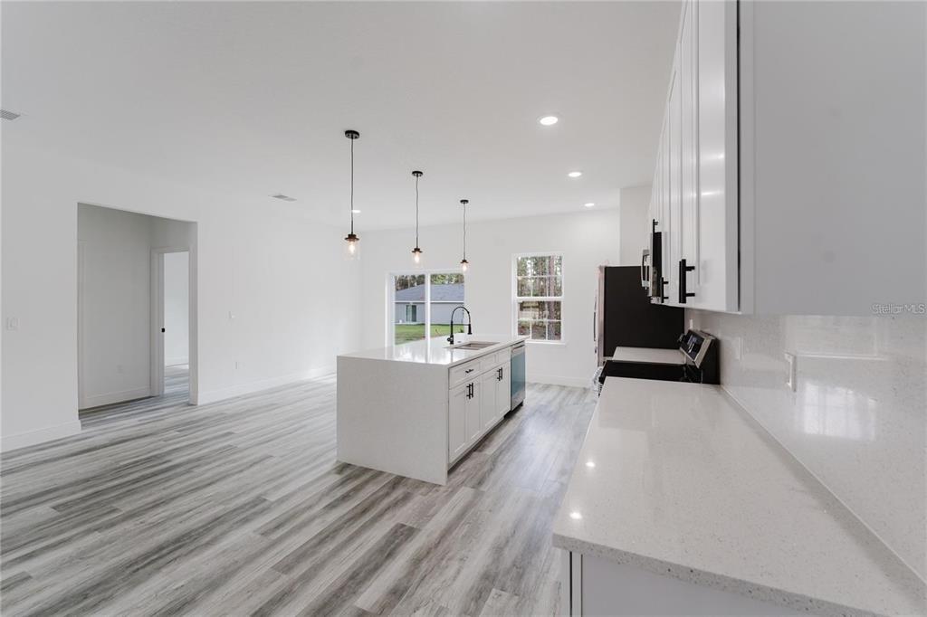6732 Southwest 132nd Street Ocala, FL 34473 - Photo 9 of 36 a large white kitchen with wooden floors and white walls
