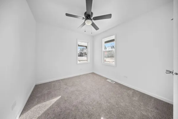 an empty room with windows and fan