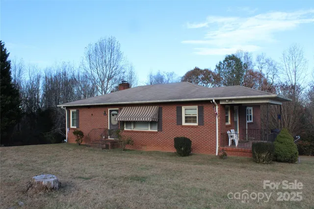 a view of a house with a yard and large tree