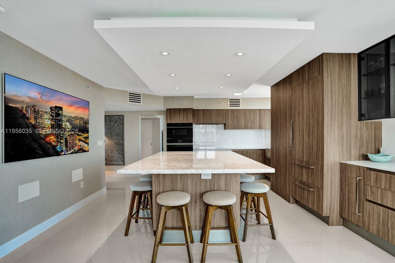 90 Alton Road, Unit 2701 Miami Beach, FL 33139 - Photo 3 of 76 a kitchen with stainless steel appliances kitchen island granite countertop a table and chairs in it