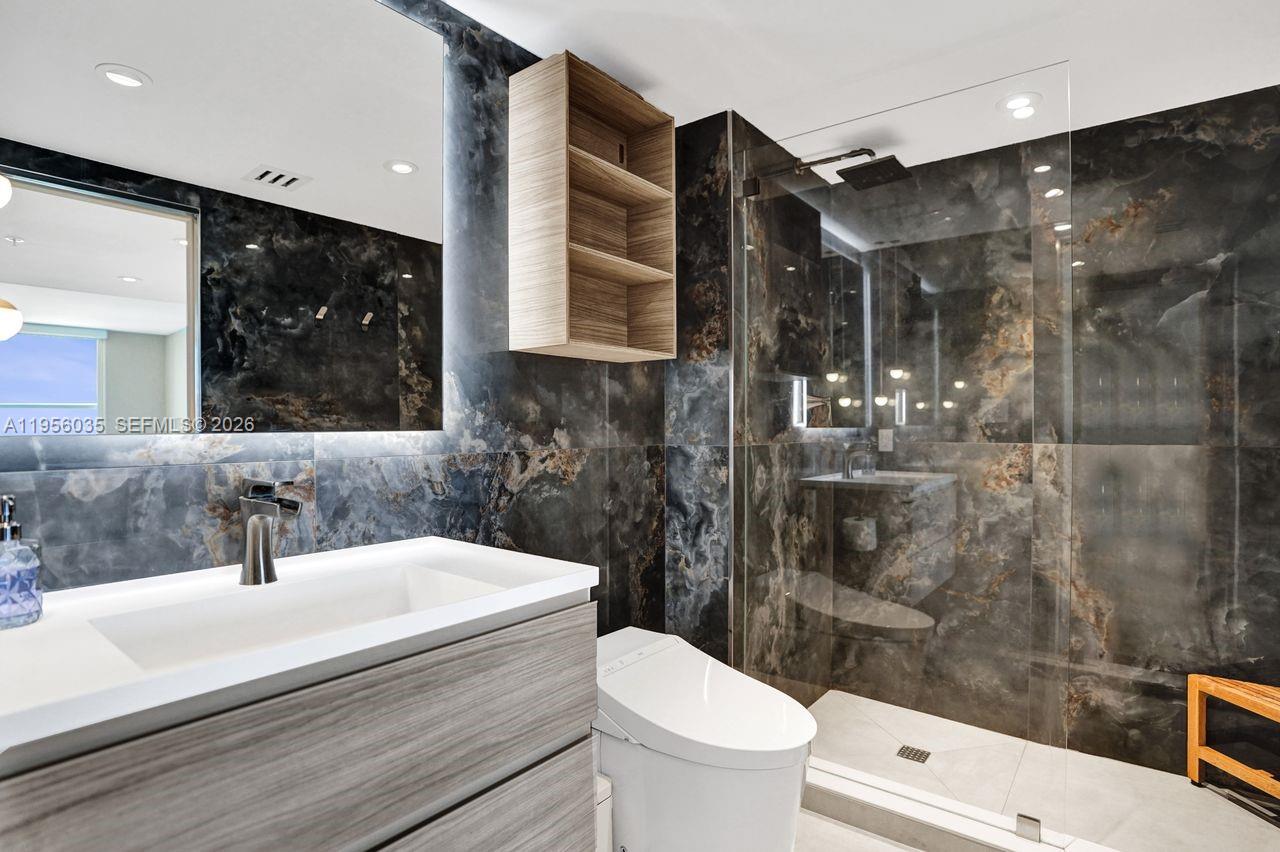 90 Alton Road, Unit 2701 Miami Beach, FL 33139 - Photo 64 of 76 a bathroom with a sink a toilet a mirror and shower