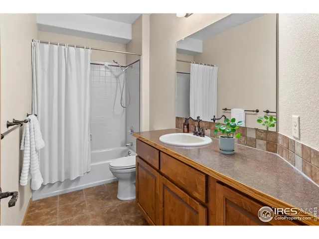 a bathroom with a granite countertop sink a toilet a mirror and shower