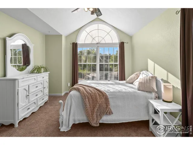 a bedroom with a bed a mirror on dresser and a window