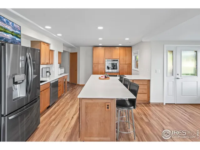 a open kitchen with stainless steel appliances granite countertop a refrigerator a stove and a wooden cabinets