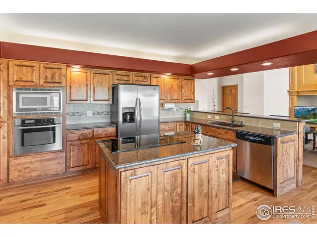 a kitchen with stainless steel appliances granite countertop a sink a stove and a refrigerator