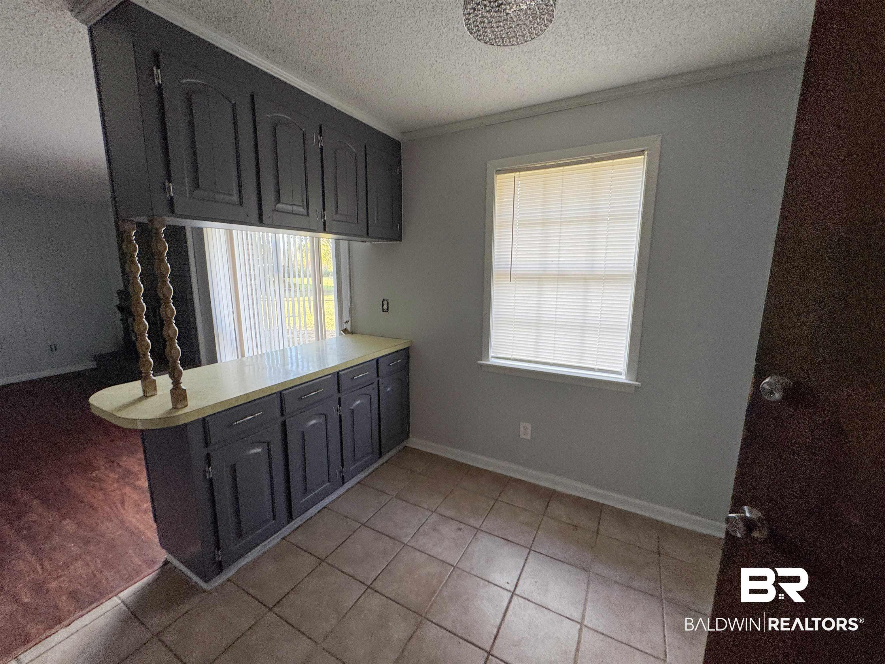 1227 Northgate Drive Atmore, AL 36502 - Photo 5 of 14 Kitchen featuring a peninsula, light countertops, a textured ceiling, light tile patterned floors, and crown molding