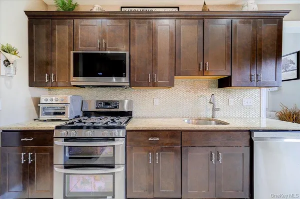 a kitchen with stainless steel appliances a stove a microwave a sink and cabinets