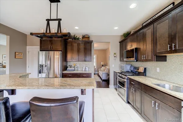 a kitchen with stainless steel appliances kitchen island granite countertop a sink stove and refrigerator