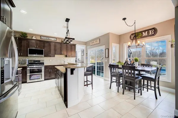 a kitchen with stainless steel appliances kitchen island granite countertop a table chairs and a stove