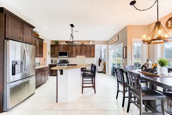 a kitchen with stainless steel appliances kitchen island granite countertop a table chairs and a refrigerator