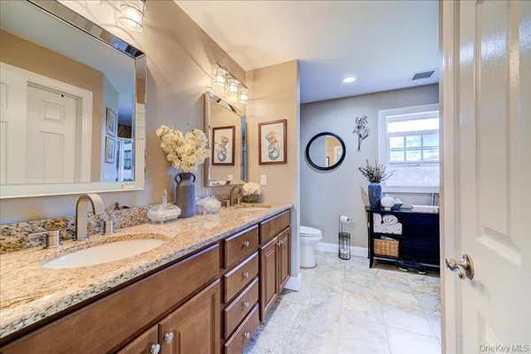 a bathroom with a granite countertop sink a toilet and a mirror