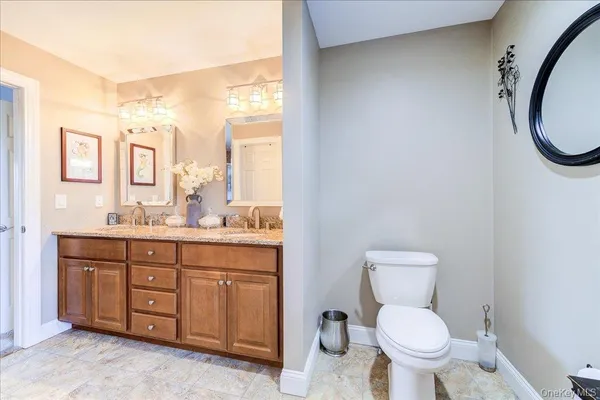 a bathroom with a granite countertop toilet sink and mirror