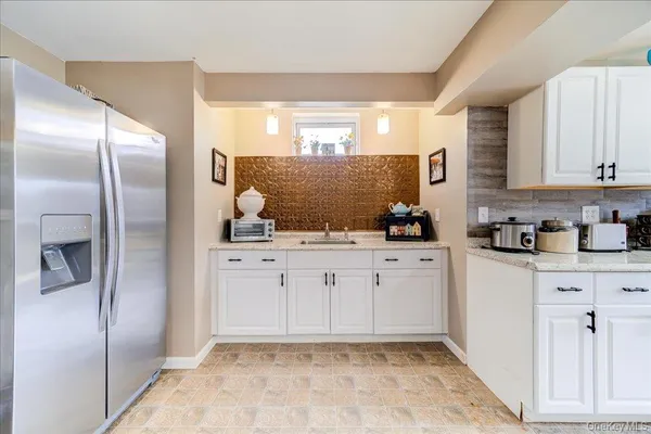 a kitchen with white cabinets and refrigerator