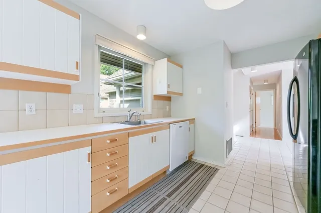 a large white kitchen with granite countertop a sink window and a granite counter top