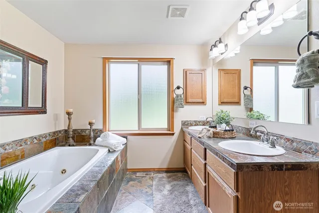 a bathroom with a tub a sink and a mirror
