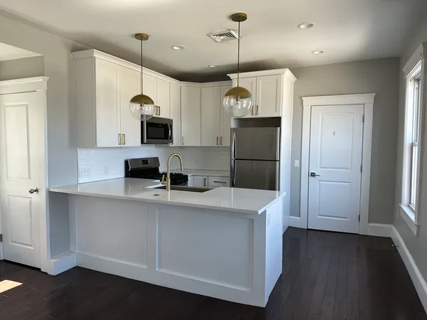 a kitchen with stainless steel appliances a refrigerator a sink a stove a microwave and wooden floor