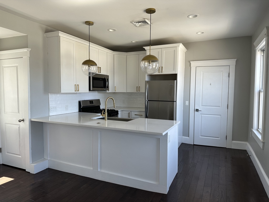 a kitchen with stainless steel appliances a refrigerator a sink a stove a microwave and wooden floor