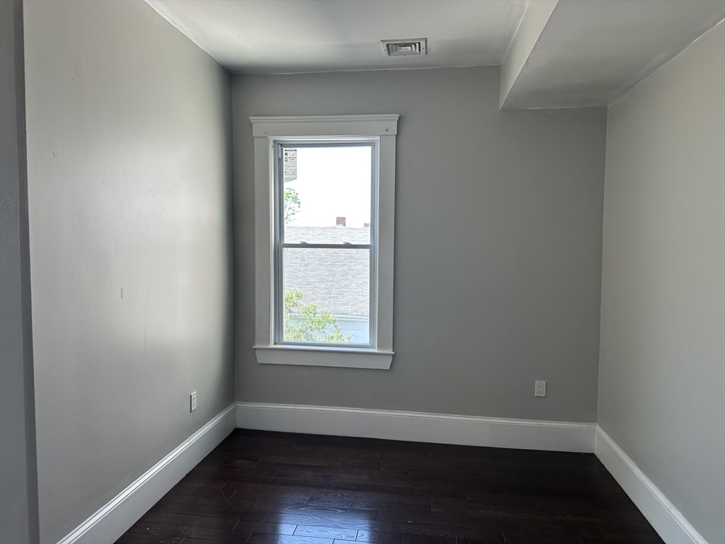 181 Chelsea Street, Unit 3 Everett, MA 02149 - Photo 4 of 10 an empty room with wooden floor and windows