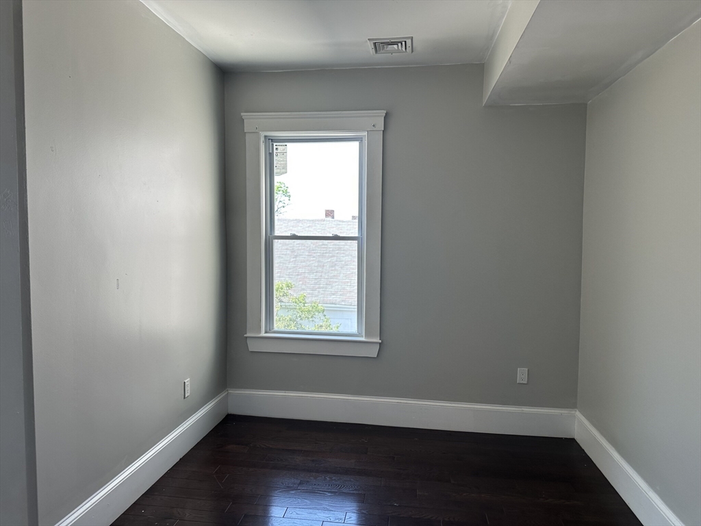 181 Chelsea Street, Unit 3 Everett, MA 02149 - Photo 6 of 10 an empty room with wooden floor and windows