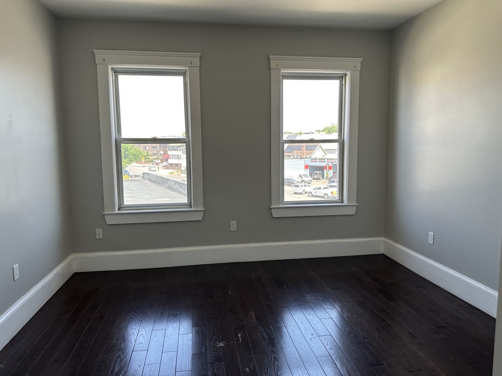 181 Chelsea Street, Unit 3 Everett, MA 02149 - Photo 8 of 10 an empty room with wooden floor and windows