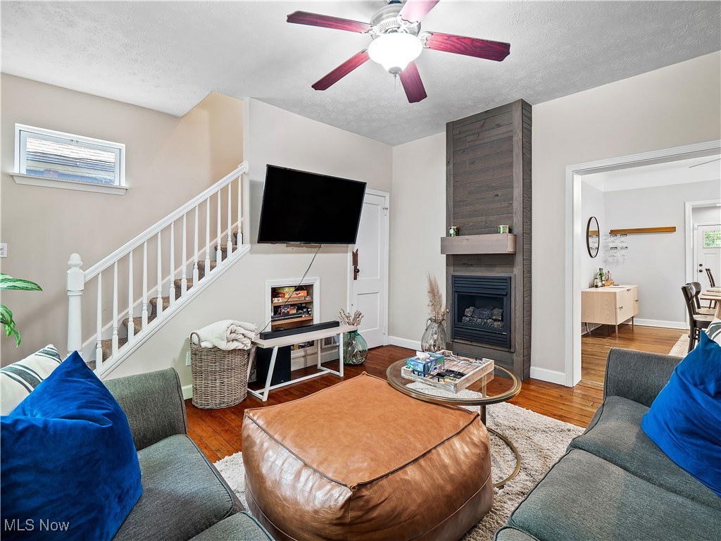 1727 Randall Road Cleveland, OH 44113 - Photo 15 of 40 Living area featuring stairs, a ceiling fan, wood finished floors, a large fireplace, and a textured ceiling