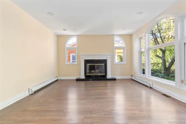 an empty room with wooden floor fireplace and windows
