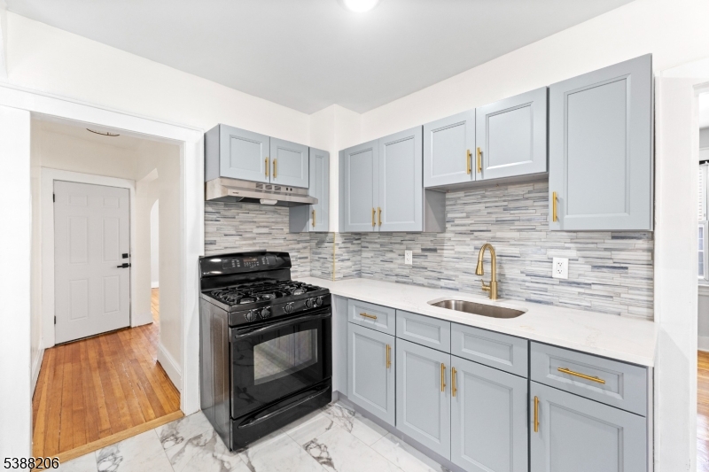 3202 Tremley Point Road Linden, NJ 07036 - Photo 24 of 41 a kitchen with cabinets stainless steel appliances a sink and wooden floor