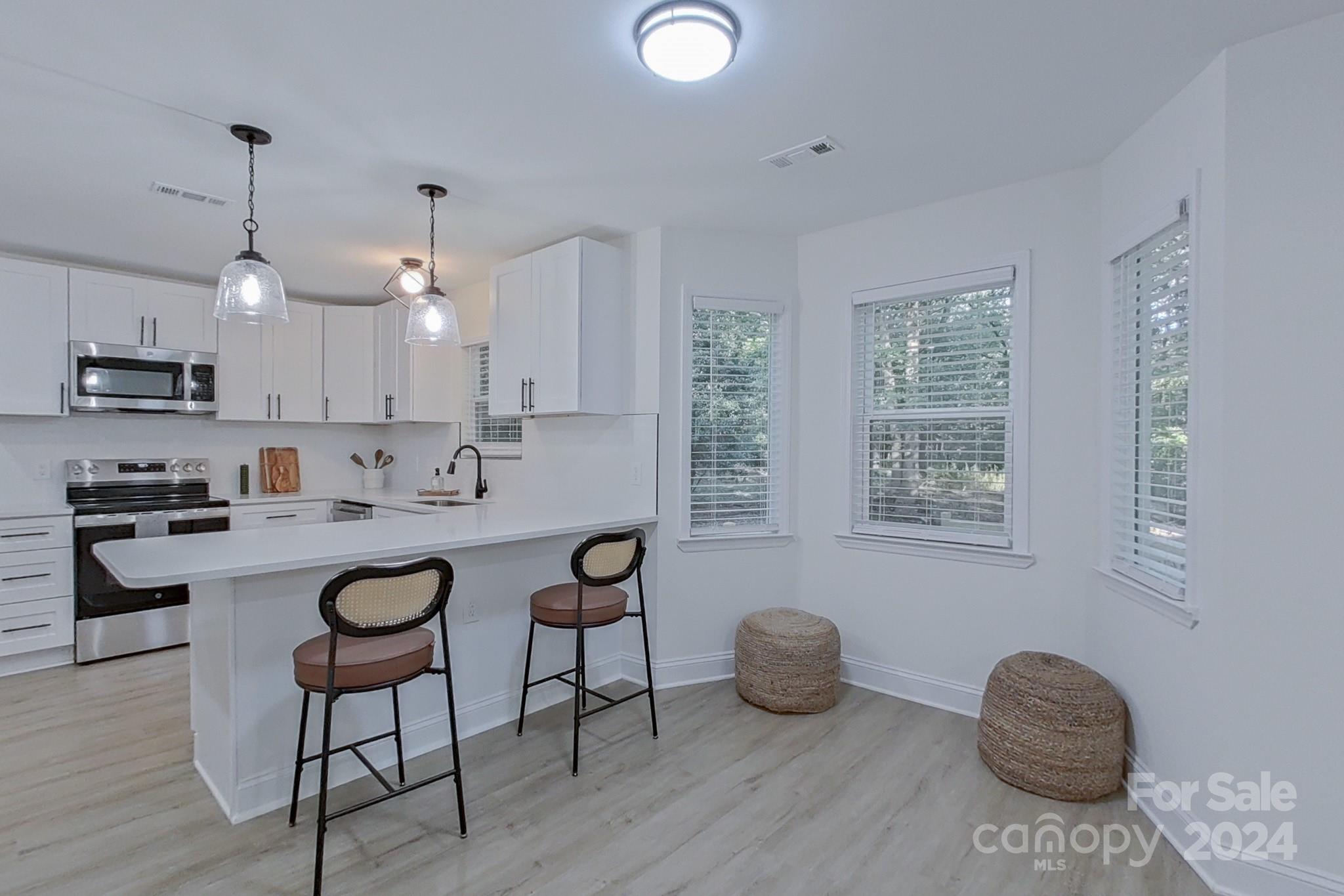 5710 Stream Ridge Drive Charlotte, NC 28269 - Photo 21 of 48 a kitchen with stainless steel appliances granite countertop a stove a sink dishwasher a dining table and chairs with wooden floor