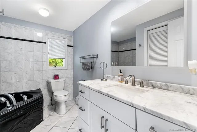 a bathroom with a granite countertop toilet a sink and a mirror