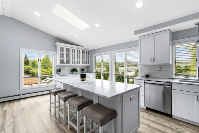 a large kitchen with granite countertop a stove top oven a sink a dining table and chairs