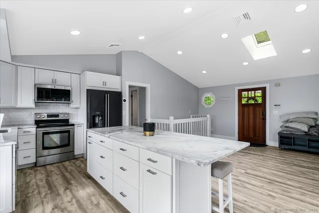 a kitchen with stainless steel appliances kitchen island granite countertop a stove and a sink
