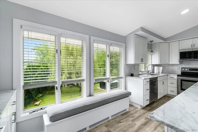 a kitchen with kitchen island a large window cabinets a sink and stainless steel appliances