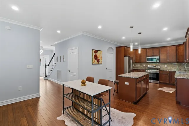 a living room with stainless steel appliances furniture and wooden floor