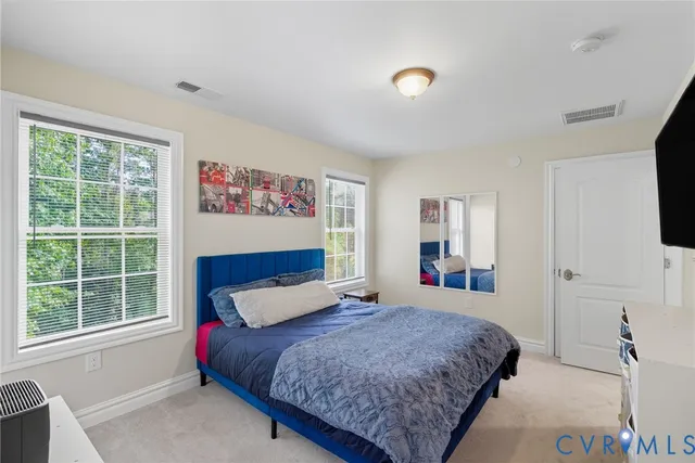 a bedroom with a large bed and a flat tv screen on dresser