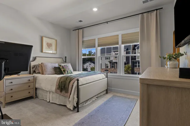 a spacious bedroom with a large bed and a flat tv screen on dresser