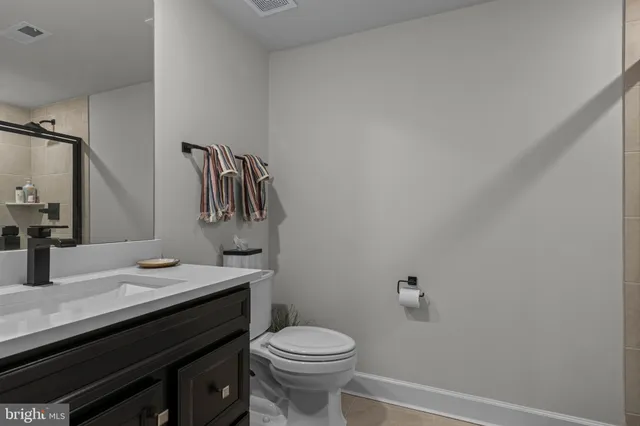 a bathroom with a granite countertop toilet sink and mirror