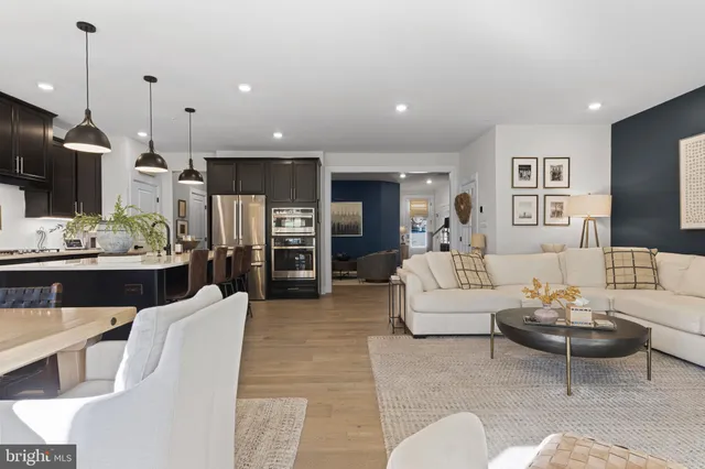 a living room with furniture kitchen view and a chandelier