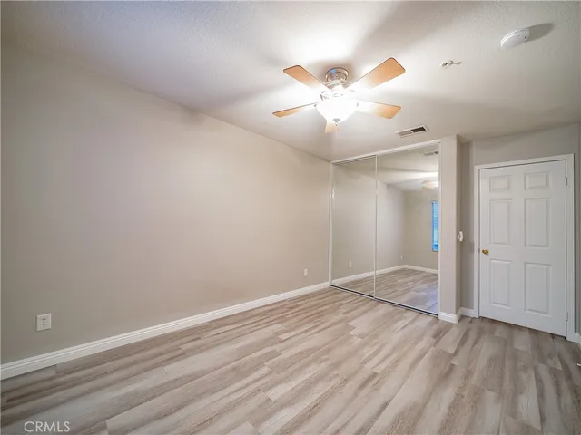 an empty room with wooden floor fan and windows