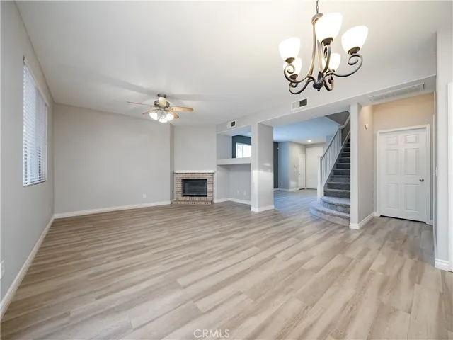 a view of a livingroom with a fireplace a chandelier and wooden floor