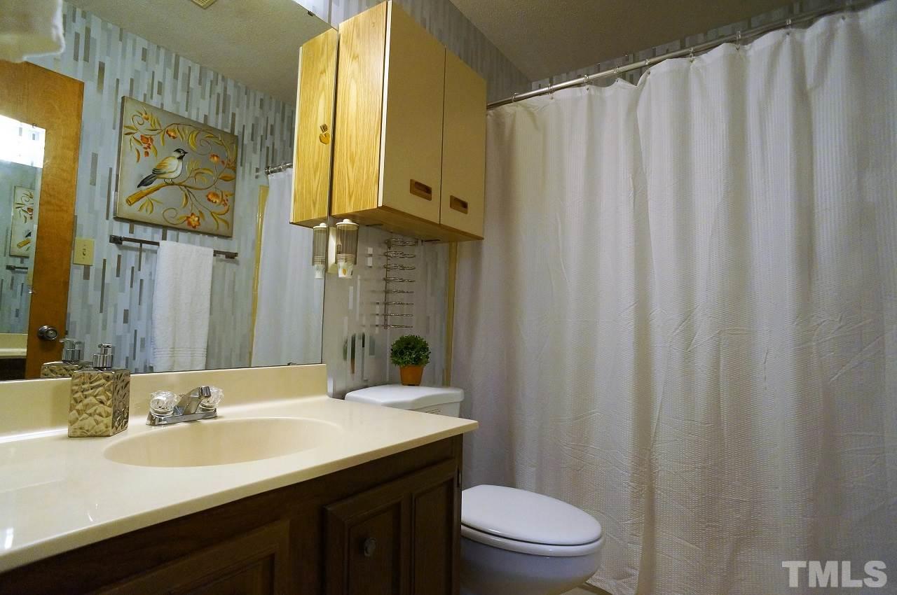 5803 Mapleridge Road Raleigh, NC 27609 - Photo 11 of 23 a bathroom with a sink a toilet and shower curtain