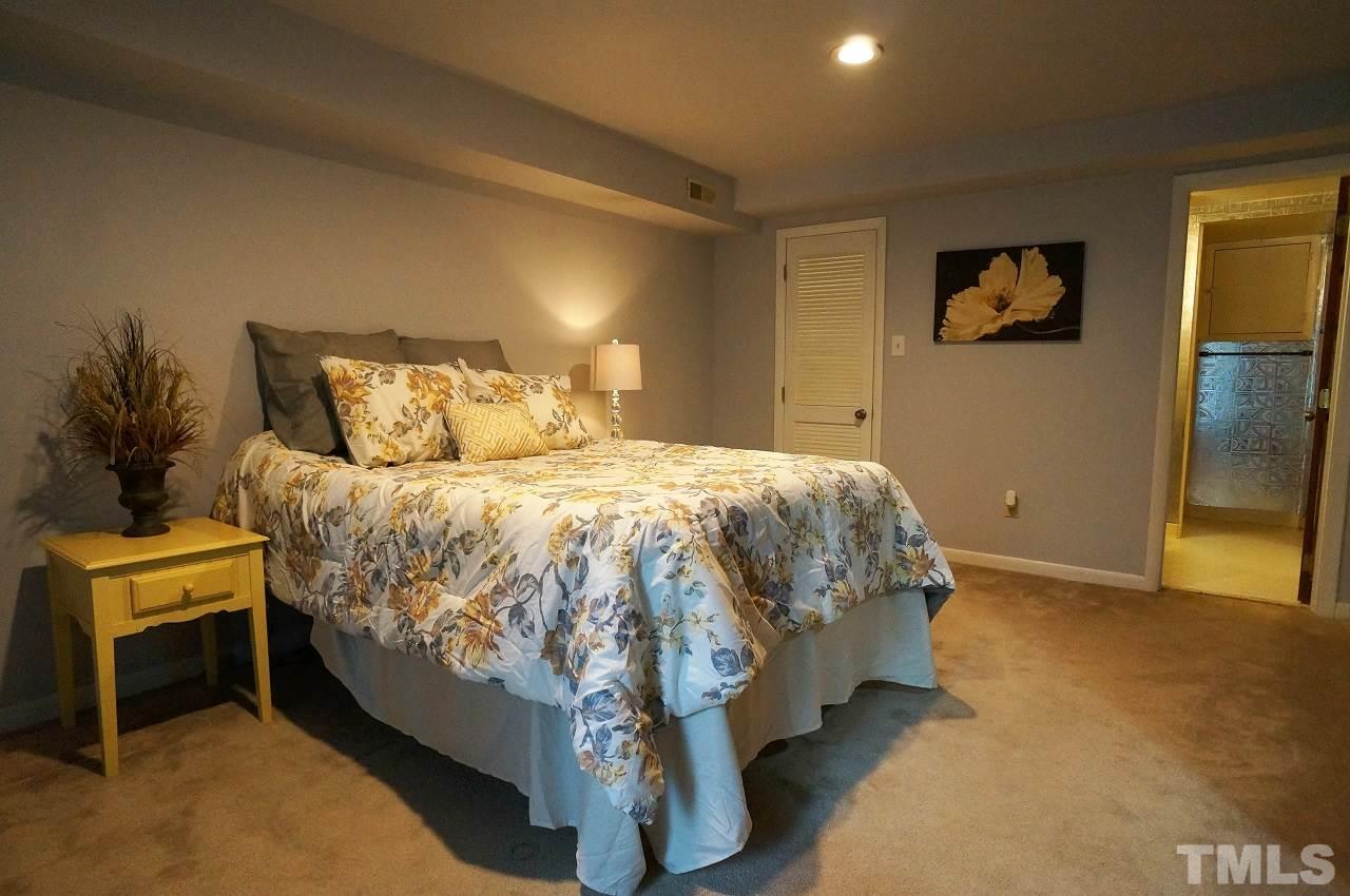 5803 Mapleridge Road Raleigh, NC 27609 - Photo 17 of 23 a bed sitting in a bedroom next to a window and a lamp