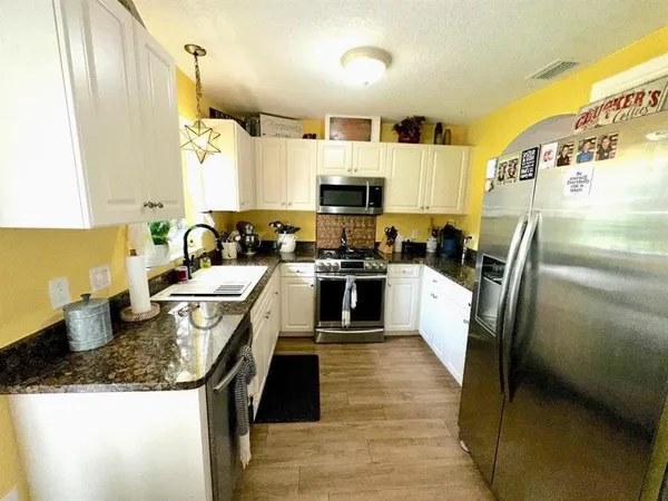 a kitchen with stainless steel appliances granite countertop a sink a stove and a refrigerator