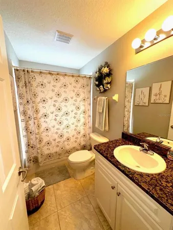 a bathroom with a granite countertop sink toilet a mirror and shower curtain