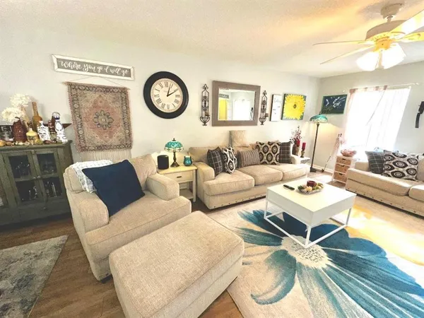 a living room with furniture a clock on wall and a window