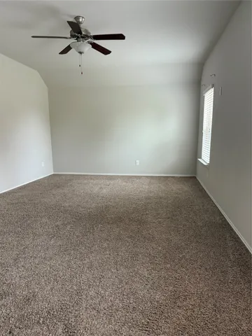 an empty room with a window and a fan