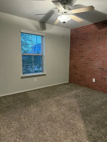 a view of an empty room with a ceiling fan and window