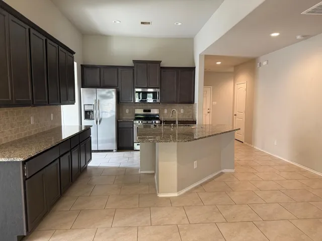 a kitchen with granite countertop a refrigerator a stove a sink a washer and dryer with wooden floor