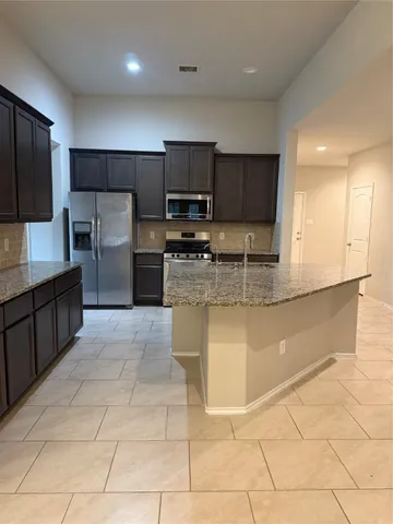 a kitchen with stainless steel appliances granite countertop a refrigerator and a stove