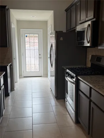 a kitchen with granite countertop a refrigerator a stove a microwave and cabinets