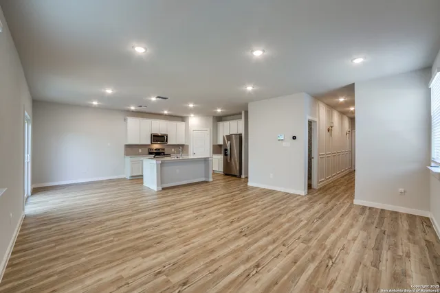 a view of kitchen with kitchen island wooden floor appliances and cabinets